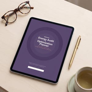 Könnte beinhalten: Ein digitales Tablet mit einem lila Bildschirm mit dem Text "Personal Energy Audit Optimization Planner". Das Tablet liegt auf einer hellen Holzoberfläche, zusammen mit einer Brille, einem goldenen Stift und einer Tasse Tee.