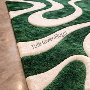 May include: A rectangular green and white area rug with a wavy design. The rug features a deep green background with flowing, cream-colored, wave-like patterns. The text "TuftHavenRugs" is visible on the rug.