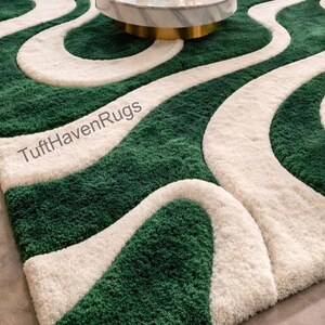 May include: A green and white patterned rug with a wavy design. The rug has a plush texture and features a repeating pattern of green and white stripes. The text "TuftHavenRugs" is visible on the rug.