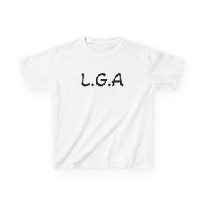 Peut inclure: Un t-shirt blanc à manches courtes avec le texte noir L.G.A imprimé dans une police grasse et arrondie au centre de la poitrine. Le vêtement présente un col rond standard et un dos ainsi que des manches d'un blanc uni sans aucun autre motif.