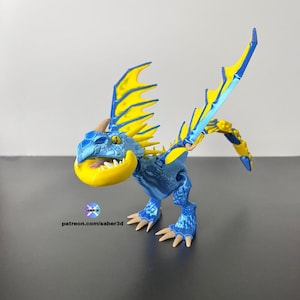 May include: A white ceramic mug with a black handle and the text "But First, Coffee" in a bold, black font. The mug is set against a blurred background, suggesting a cozy setting.