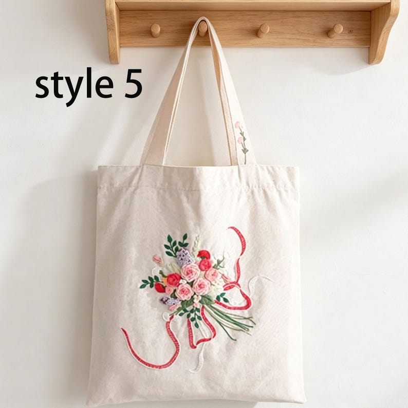 May include: Off-white tote bag with embroidered floral bouquet design. The bouquet features pink, red, and purple flowers with green leaves and red ribbons. The text "style 5" is printed on the bag.