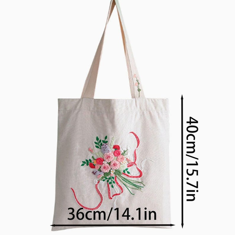 May include: Cream-colored tote bag with embroidered floral design. The bag features a bouquet of pink, red, and purple flowers with green leaves and red ribbons. The bag is 14.1 inches wide and 15.7 inches tall.