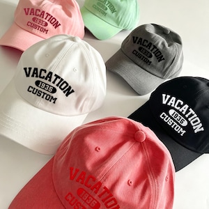 Könnte beinhalten: Eine Sammlung von sechs Baseballkappen in verschiedenen Farben, darunter Rosa, Hellgrün, Weiß, Grau, Schwarz und Koralle. Jede Kappe ist mit dem gestickten Text VACATION 1935 CUSTOM in einer passenden oder kontrastierenden Garnfarbe versehen.
