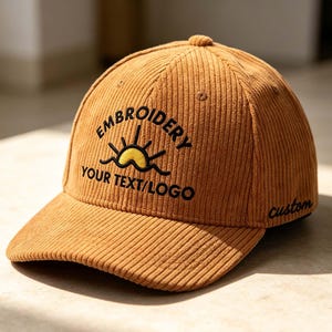 May include: A tan corduroy baseball cap featuring an embroidered design of a yellow sun rising over black waves. The text EMBROIDERY YOUR TEXT/LOGO is stitched in black above the sun, and the word custom is embroidered in black on the side panel.