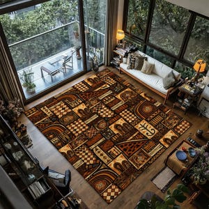 May include: A large, rectangular area rug with a geometric pattern in shades of brown, tan, and cream. The design features squares, rectangles, and abstract shapes. The rug is placed in a living room with a sofa and large windows.