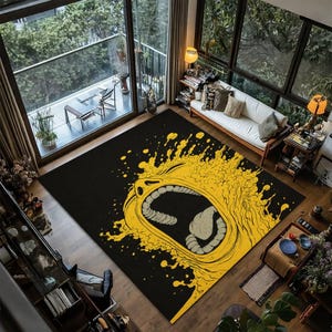 May include: Black rectangular area rug with a large yellow graphic of an open mouth with a screaming expression. The rug is placed on a wooden floor in a room with large windows and a balcony.