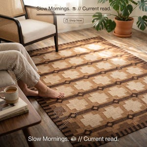 Può includere: Un tappeto rettangolare caratterizzato da un motivo geometrico ripetitivo nei toni del marrone e del crema. Il design è composto da forme a croce marrone scuro alternate a blocchi color crema disposti a griglia, con un bordo a righe.
