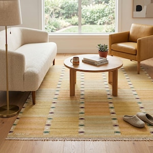 May include: A rectangular area rug featuring a grid pattern of muted yellow, orange, and green squares separated by thin, dark-accented borders. The rug has a short fringe along the edge and displays the word ABLIME in the bottom left corner.