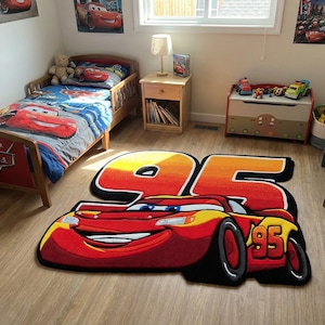 Può includere: Camera da letto per bambini con un tappeto di Saetta McQueen rosso e giallo con il numero 95. La stanza comprende un letto con una trapunta a tema Cars, opere d'arte murali e un baule dei giocattoli. È visibile una libreria in legno.