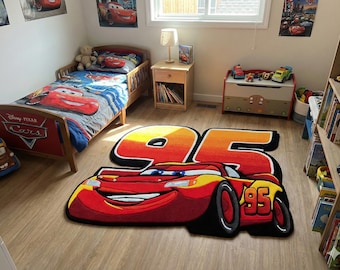 May include: A children's bedroom featuring a red and yellow Lightning McQueen rug with the number 95. The room includes a bed with a Cars-themed comforter, matching wall art, and a toy chest. A wooden bookshelf is visible.