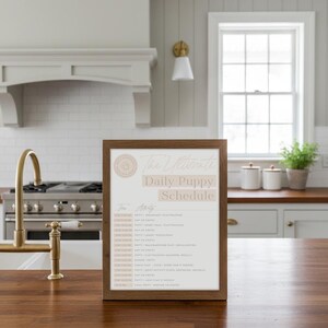 Op de afbeelding: Een houten lijst met de tekst "The Ultimate Daily Puppy Schedule" in een keuken. De planning beschrijft de dagelijkse routine van een puppy, inclusief maaltijden, spel en rusttijden. De lijst is bruin en de achtergrond is neutraal beige.