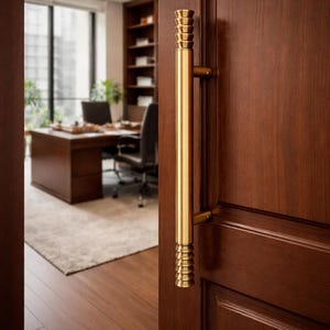 May include: A close-up of a wooden door with a gold-colored handle. The door is a rich, dark brown color. The handle is cylindrical with decorative ridges at each end. The door opens to reveal an office space.