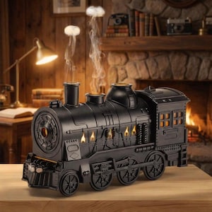 May include: Black decorative train with illuminated windows and smokestacks. The train has a vintage design with visible wheels and a front headlight. Smoke-like vapor rises from the smokestacks, creating a visual effect. The train is placed on a wooden surface.