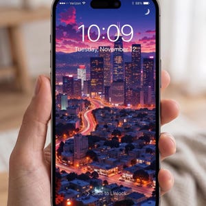 May include: A smartphone displays a cityscape at dusk with a vibrant sky. The screen shows the time as 10:09 and the date as Tuesday, November 12. The phone is held in a hand.