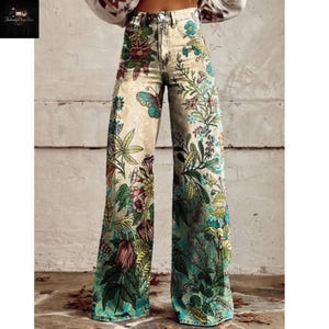 May include: Wide-leg jeans with a floral and butterfly print. The pants feature a beige background with colorful flowers, leaves, and a blue butterfly. The design extends from the waist to the hem, creating a vibrant, eye-catching look.