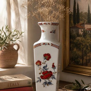 Può includere: Un alto vaso in porcellana bianca a base quadrata con un motivo floreale dipinto a mano raffigurante papaveri rossi vivaci e fogliame blu-verde. Il collo e la base sono decorati con un delicato motivo geometrico rosso e blu, contenente gipsofila.