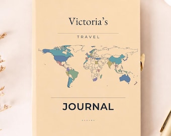 Può includere: Un diario di viaggio color beige chiaro con un'illustrazione di una mappa del mondo con paesi multicolori. La copertina riporta la scritta Victoria's TRAVEL JOURNAL in blu scuro, con una penna dorata sul lato destro.