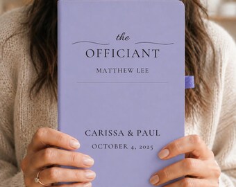 Può includere: Un taccuino viola chiaro con un piccolo passante elastico viola sul lato. La copertina presenta un testo nero che recita: the OFFICIANT, MATTHEW LEE, CARISSA & PAUL, e OCTOBER 4, 2025, con una linea orizzontale decorativa sopra la parola OFFICIANT.