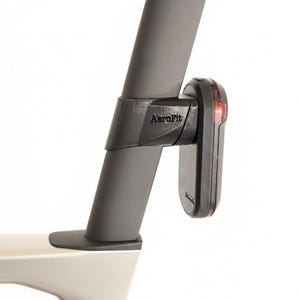 Könnte beinhalten: Ein schwarzes AeroFit-Fahrradzubehör ist an einem grauen Fahrradbauteil montiert. Das Zubehör hält ein schwarzes Gerät mit rotem Licht. Der Text "AeroFit" ist auf dem Zubehör sichtbar.