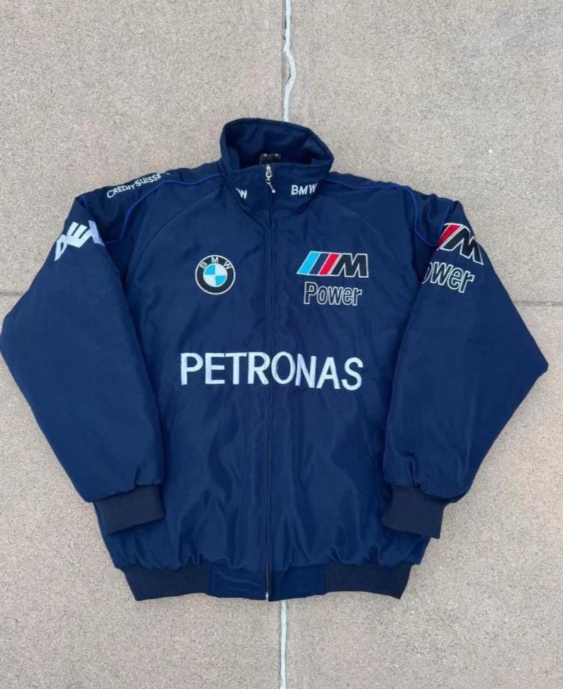 May include: Navy blue zip-up jacket with the BMW logo and "PETRONAS" printed in white. The jacket features "M Power" and "Credit Suisse" branding. The jacket has a stand-up collar and black ribbed cuffs and hem.