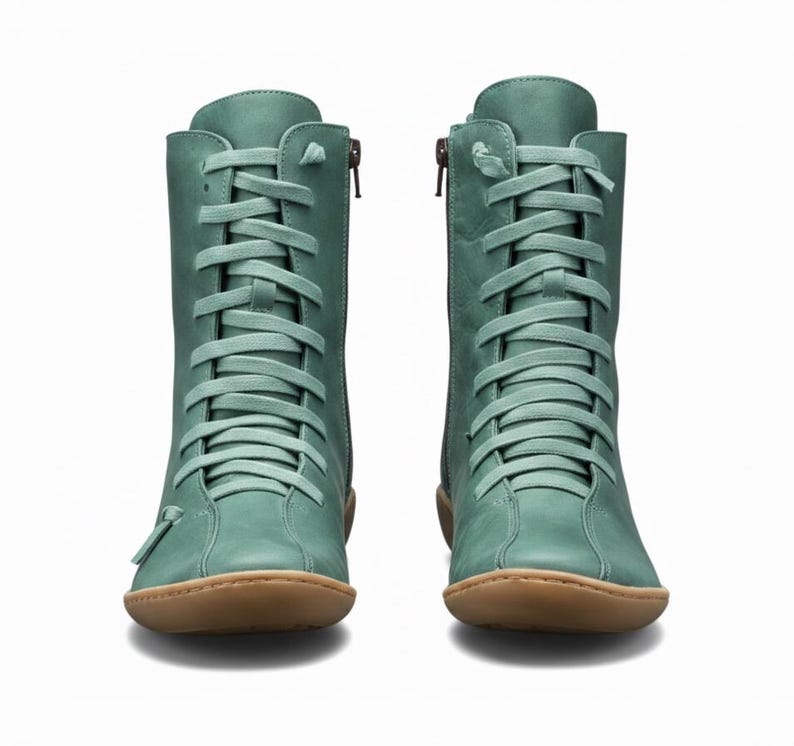 K&ouml;nnte beinhalten: Ein Paar tealfarbene kn&ouml;chelhohe Stiefel mit Schn&uuml;rung und seitlichen Rei&szlig;verschl&uuml;ssen. Die Stiefel haben eine runde Spitze und eine braune Sohle. Die Schn&uuml;rsenkel und das Leder sind gleichfarbig. Vor wei&szlig;em Hintergrund.