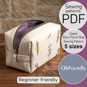 Op de afbeelding: Een beige boxy etui met een rits, geborduurd met kleurrijke bloemen. De binnenkant is paars. De afbeelding bevat de tekst "Sewing patterns PDF", "Zipper Boxy Pouch Bag Sewing Pattern 5 sizes" en "Beginner friendly".