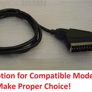 Op de afbeelding: Zwarte SCART-kabel met een ronde en een rechthoekige connector. De kabel is opgerold. De tekst luidt "Check Description for Compatible Models And To Make Proper Choice!"