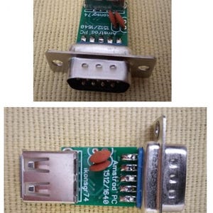 Può includere: Una scheda a circuito stampato verde con un connettore USB e un connettore seriale. La scheda riporta la scritta "Amstrad PC 1512/1640" e "ikonsgr74". I connettori sono argentati e la scheda presenta piccoli componenti elettronici.