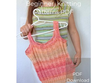 May include: A knitted tank top in shades of peach, pink, and orange is held on a white hanger. The top has a textured, open-weave design. The image also includes the text "Beginner Knitting Patterns PDF Download."