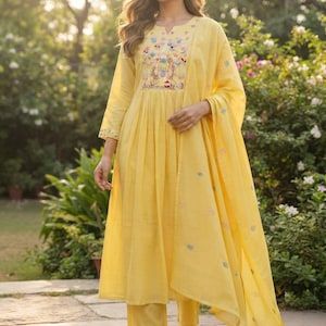 Pode incluir: Um conjunto de três peças amarelo brilhante composto por uma túnica kurta até ao joelho com decote em entalhe, calças de perna reta e uma dupatta a condizer. A túnica apresenta um bordado floral intrincado no peito e nos punhos.