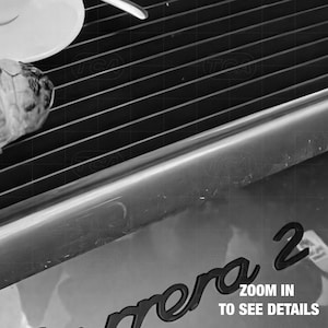 a close-up view of a camera lens, with the text "Zoom in to see details" visible.