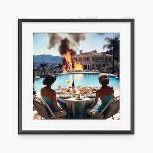 May include: A framed print depicts two women seated at a table set for a meal, overlooking a pool and a burning mansion. The women wear blue dresses. The table is set with plates, glasses, and food. A fire rages in the background, with smoke billowing into the sky.