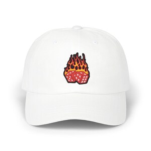 May include: White baseball cap with a curved brim. The cap features an embroidered patch of two red dice engulfed in flames with yellow and orange accents. The cap is made of a soft, durable fabric.