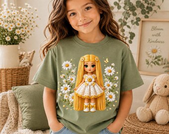 Könnte beinhalten: Ein olivgrünes Kurzarm-T-Shirt mit einem Grafikdruck einer Puppe mit langem gelbem Haar, die ein weißes Kleid mit einer gelben Blume in der Mitte trägt. Die Puppe ist auf der Vorderseite des Shirts von weißen Gänseblümchen und gelben Schmetterlingen umgeben.