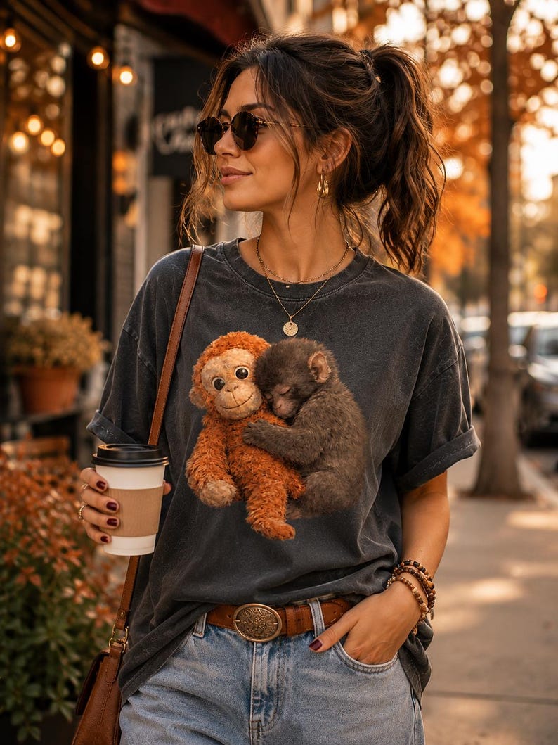 Cute monkey lover t-shirt featuring viral baby monkey artwork on Comfort Colors apparel. Coordinated couple outfit photographed in a modern lifestyle setting with oversized vintage fit.