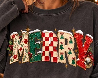 Könnte beinhalten: Ein anthrazitfarbenes Sweatshirt mit Rundhalsausschnitt und dem Wort MERRY in großen, strukturierten Buchstaben. Die Buchstaben sind mit roten und grünen Mustern verziert, darunter Stechpalmen, ein rot-weißes Schachbrettmuster, Tannenbäume und eine goldene Discokugel.