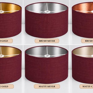 Peut inclure: Six abat-jours cylindriques en forme de tambour avec un extérieur en tissu bordeaux foncé. Les intérieurs présentent des finitions métalliques étiquetées Brush Gold, Brush Silver, Brush Copper, Matte Gold, Matte Silver et Matte Champagne.