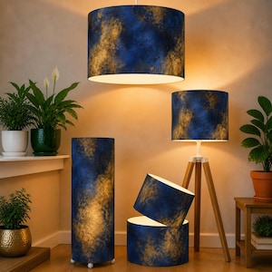 May include: A selection of lampshades and lamps featuring a blue and gold abstract pattern. The lamps include a pendant light, a floor lamp, a table lamp, and two smaller shades. The room also contains several potted plants.
