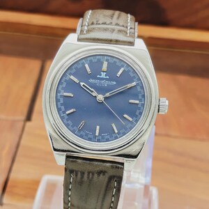 Puede incluir: Un reloj Jaeger-LeCoultre Club plateado con esfera azul oscuro y correa de cuero marr&oacute;n. El reloj tiene marcadores de hora y agujas plateadas, y la correa est&aacute; cosida con hilo blanco. La esfera del reloj dice "Jaeger-LeCoultre Club".