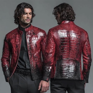 Puede incluir: Chaqueta de cuero roja y negra con un patrón texturizado similar al de un cocodrilo. La chaqueta tiene cuello alto y cierre de cremallera. Las mangas y la parte inferior de la espalda son negras, el resto de la chaqueta es roja.