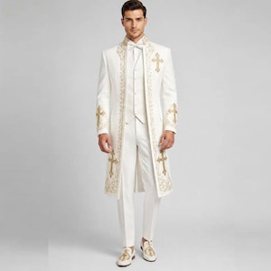 May include: A white three-piece suit consisting of a long coat, a vest, and trousers. The long coat features gold embroidered cross motifs and intricate scrollwork patterns along the front panels and sleeves. A white bowtie is worn at the neck.