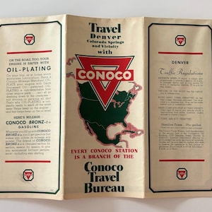 May include: Vintage Conoco Travel Bureau brochure. The brochure features a red, white, and green Conoco logo with a map of North America. Text includes "Travel Denver Colorado Springs and Vicinity with Conoco". The brochure is folded.
