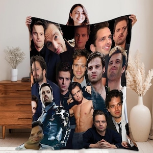 May include: A black blanket with a collage of images of a man in different poses and expressions. The blanket is held up by a person, displaying the design. The images are in various sizes and arrangements.