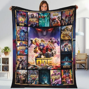 Könnte beinhalten: Eine große, rechteckige Transformers One Fleece-Decke. Die Decke zeigt eine Collage von Bildern von Transformers-Charakteren und dem Filmtitel. Das Farbschema umfasst Rot, Blau, Gelb und Lila auf schwarzem Hintergrund.