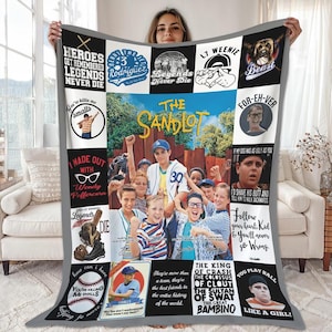 Puede incluir: Una manta gris con un collage de imágenes y texto de la película "The Sandlot". La imagen central muestra a un grupo de niños. Las imágenes circundantes incluyen citas y retratos de personajes. La manta tiene un borde gris.