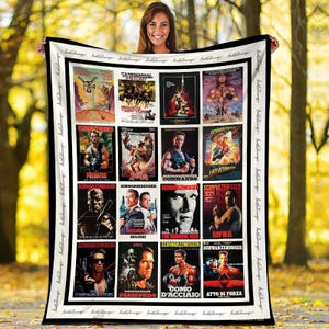 May include: A black and white blanket featuring a collage of movie posters. The posters showcase various films starring Arnold Schwarzenegger, including "Predator," "Commando," and "The Running Man." The blanket is held by a person.
