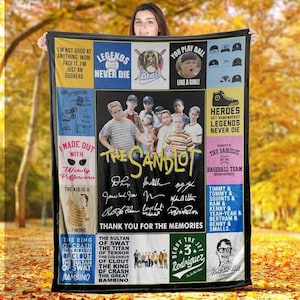 May include: A black blanket featuring a collage of images and text from the movie "The Sandlot." The blanket includes images of the cast, quotes, and the film's title. The blanket is held by a person.