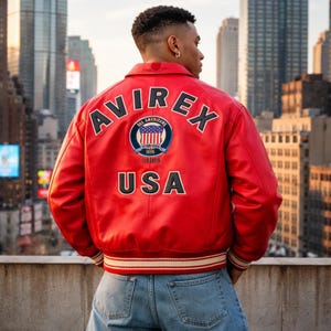 May include: A red leather jacket with the word "AVIREX" across the shoulders and "USA" at the bottom. The jacket features a circular patch with an American flag design and the words "ALL AMERICANS" and "ESTABLISHED 1975".