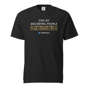 May include: Black t-shirt with the text "CEO OF DECODING PEOPLE" in white and gold. Below the text are three gold rectangles with code symbols and the word "APPROVED" with a checkmark.
